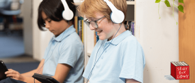 Two Students in School uniform listening to an audio book on their iPad 