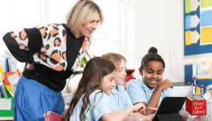 3 School children and their teacher reading on an iPad 