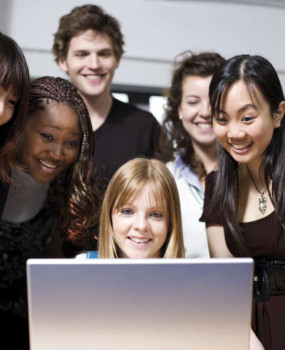 students smiling at laptop 